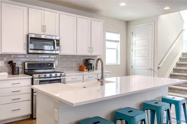 a kitchen with stainless steel appliances granite countertop a refrigerator a stove top oven a sink and dishwasher with wooden floor