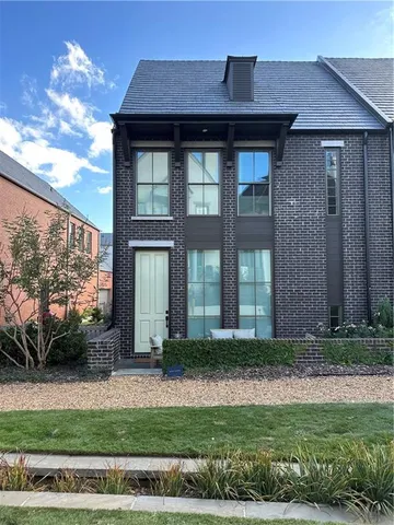 a view of a brick house with large windows and a yard