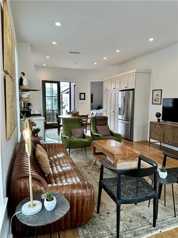 a living room with furniture and a dining table with wooden floor