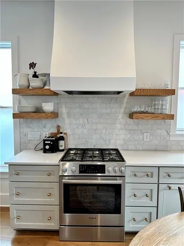 a kitchen with sink a stove and white cabinets