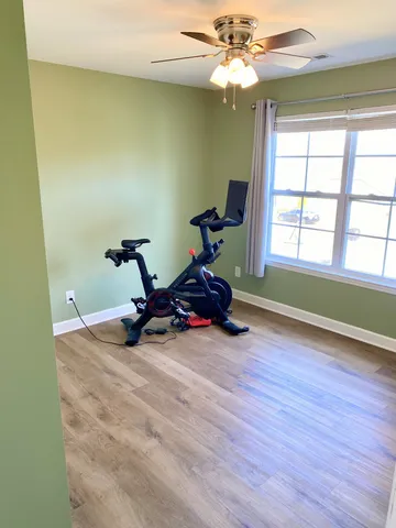 a view of a room with window a ceiling fan and wooden floor
