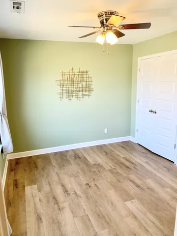 a view of a big room with wooden floor and a chandelier fan