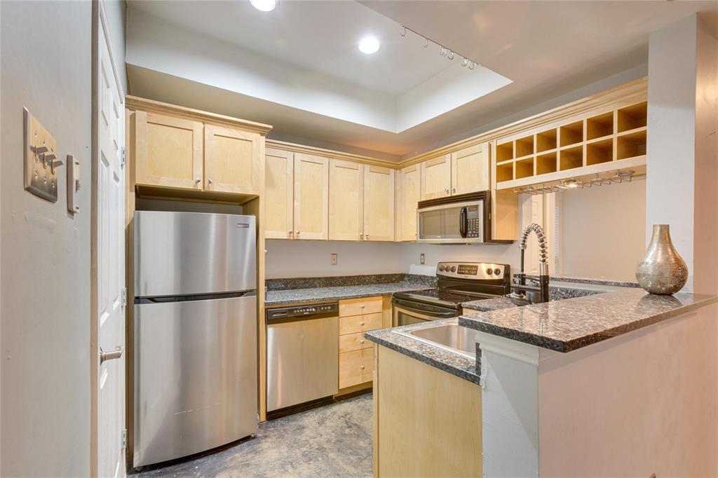 4104 North Hall Street, Unit 102 Dallas, TX 75219 - Photo 11 of 18 Kitchen featuring granite countertops, wood-finish cabinetry, stainless steel appliances, a built-in wine rack, and an undermount sink with a pull-down faucet