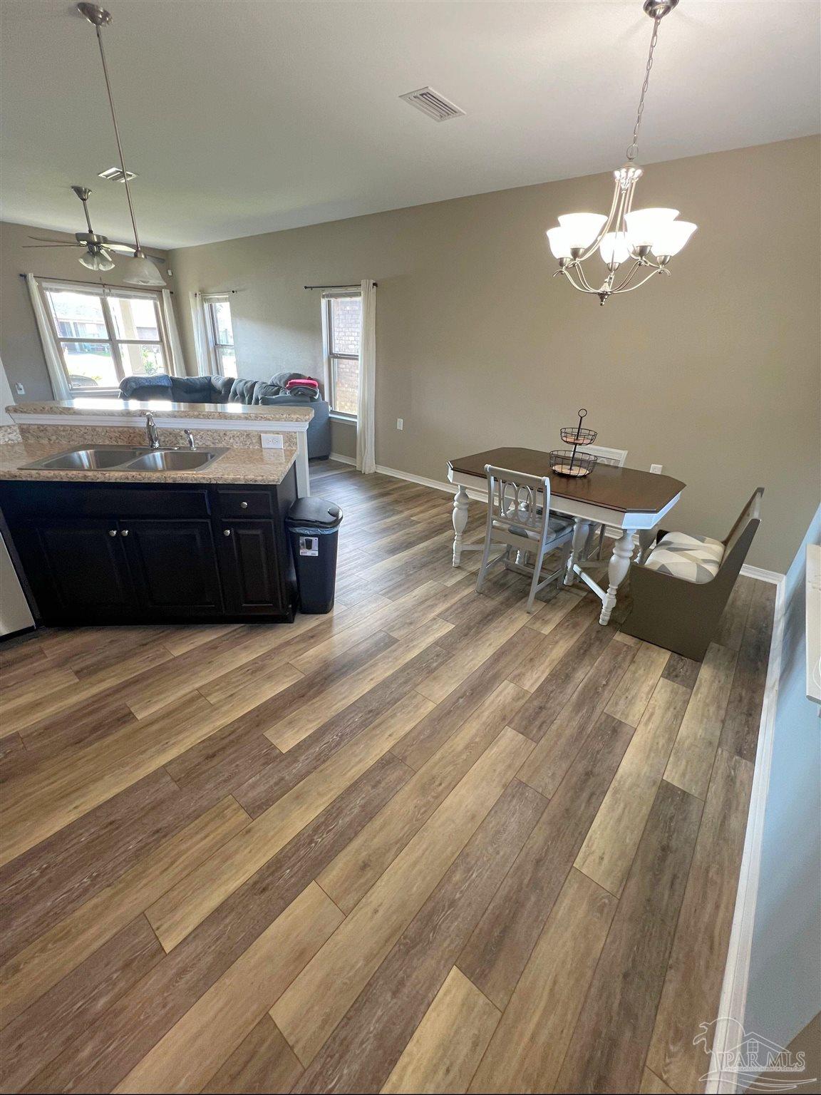 5798 Corkscrew Court Pace, FL 32571 - Photo 5 of 18 a kitchen with a chandelier and wooden cabinets