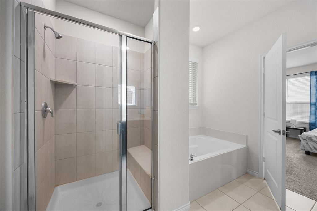 3808 High Country Road Aubrey, TX 76227 - Photo 18 of 36 Spacious bathroom featuring a glass-enclosed shower with tile surround and built-in bench, a separate soaking tub with a window, recessed lighting, and tile flooring