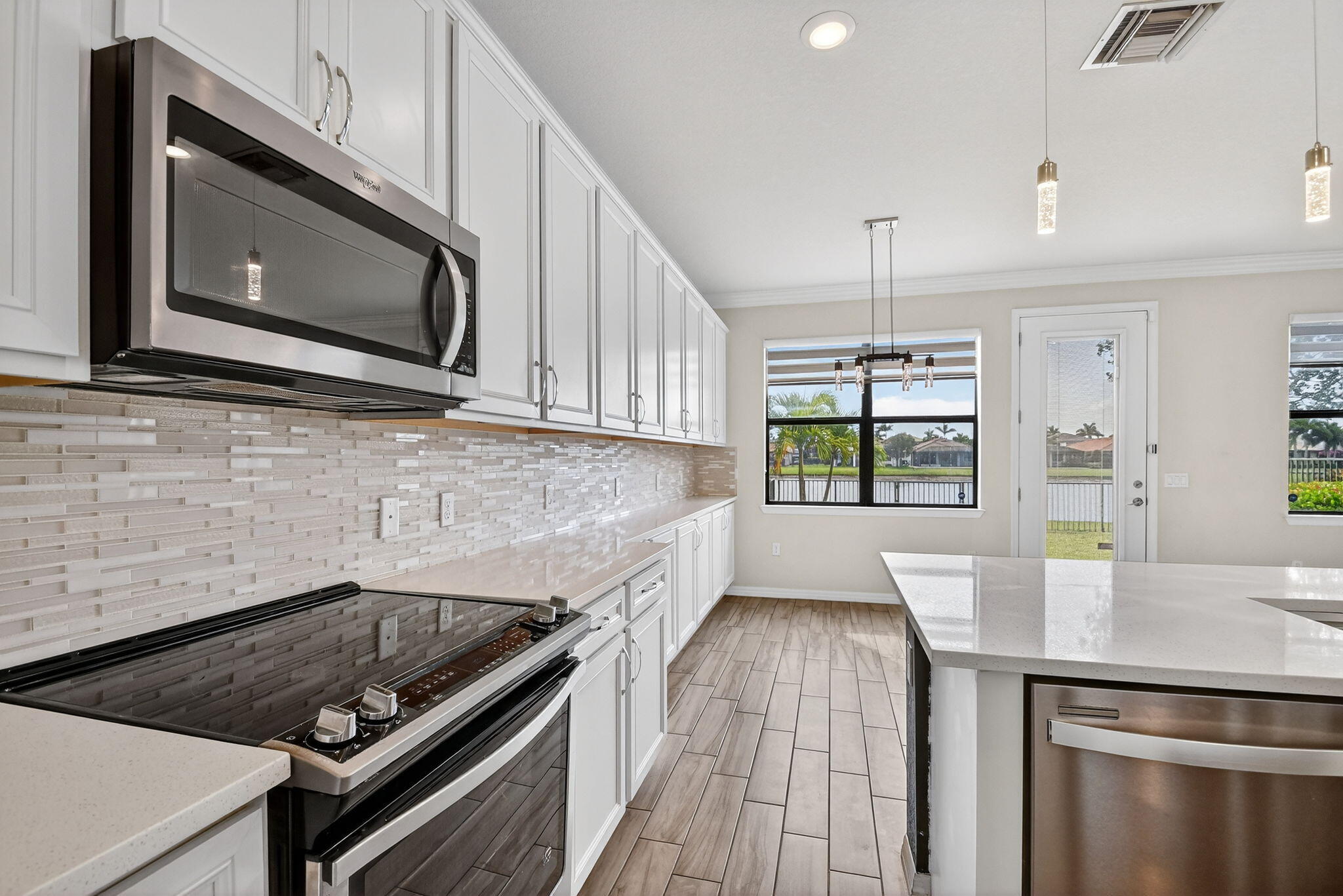 8301 Rearing Lane Lake Worth, FL 33467 - Photo 16 of 109 a kitchen with stainless steel appliances kitchen island granite countertop a stove a sink and a microwave