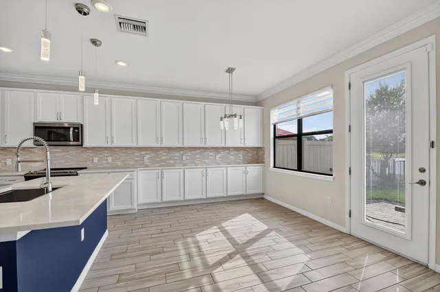 an empty room with wooden floor cabinet and windows