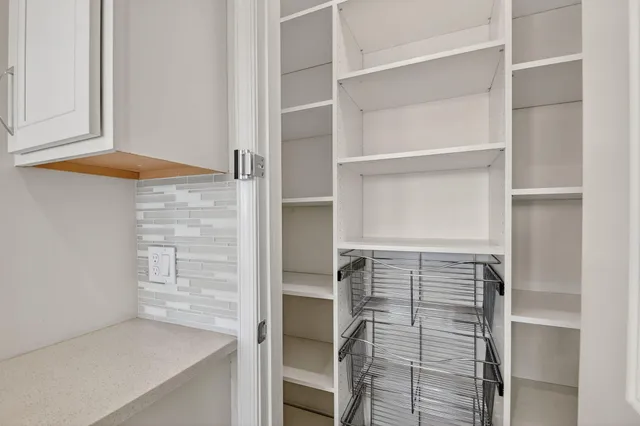 an empty room with wooden floor chandelier and windows