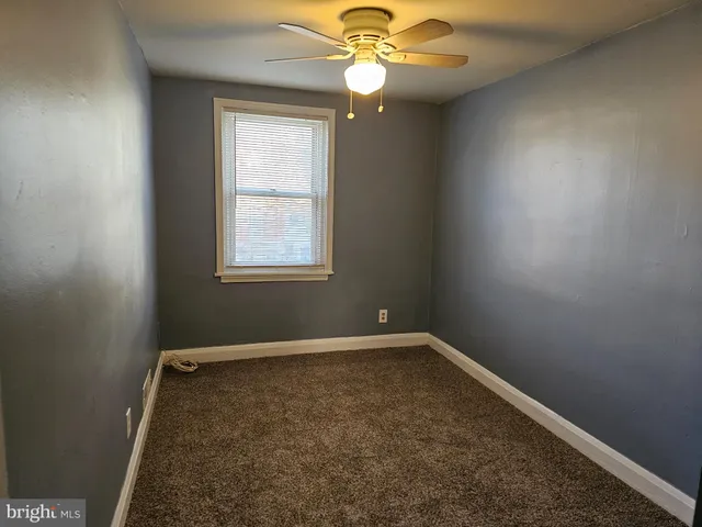 an empty room with a window and a fan