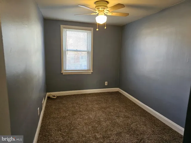 an empty room with a chandelier fan and windows