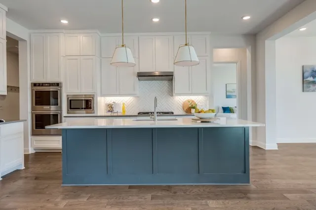 a kitchen with stainless steel appliances granite countertop a sink a stove and a refrigerator