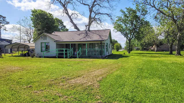 a view of a house with a big yard and large trees