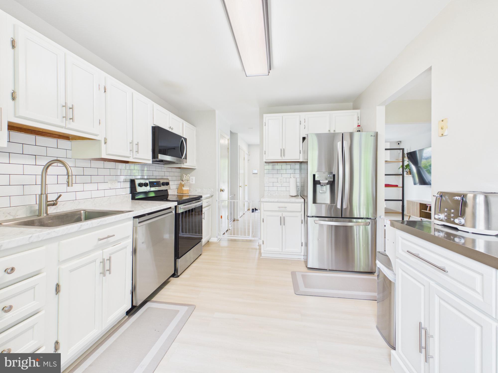 7606 Huntsman Court Clinton, MD 20735 - Photo 20 of 40 a kitchen with white cabinets and stainless steel appliances