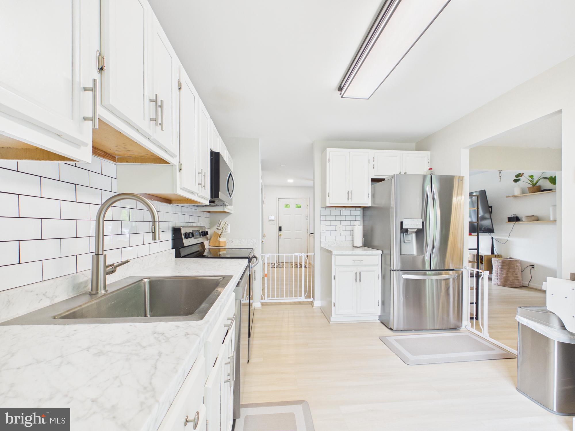 7606 Huntsman Court Clinton, MD 20735 - Photo 21 of 40 a kitchen with white cabinets and stainless steel appliances