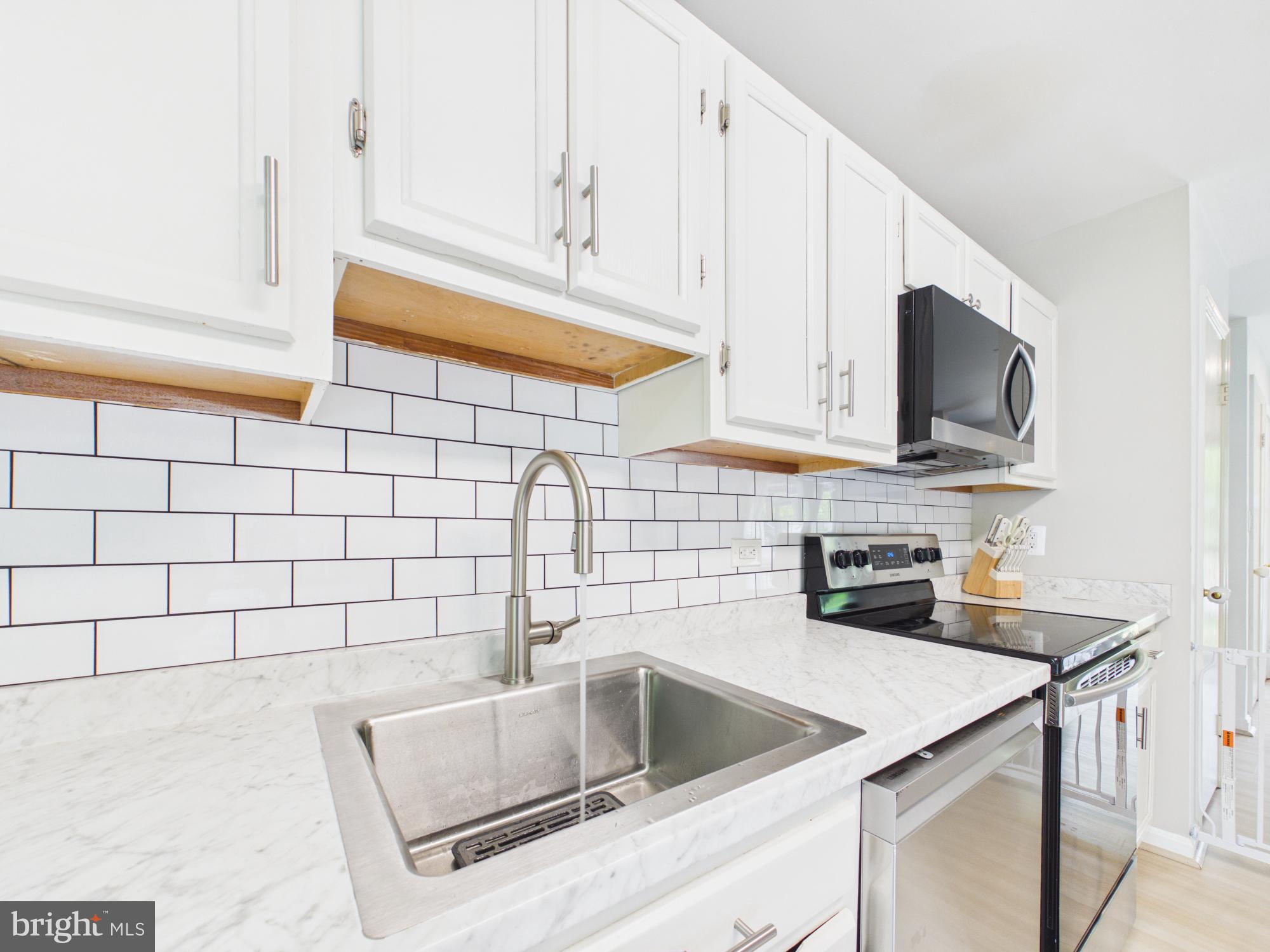 7606 Huntsman Court Clinton, MD 20735 - Photo 22 of 40 a kitchen with granite countertop white cabinets and a stove top oven