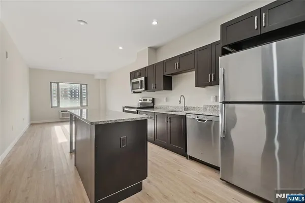 a kitchen with granite countertop a refrigerator a sink dishwasher a stove top oven a refrigerator and cabinets with wooden floor