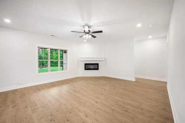 an empty room with windows and ceiling fan