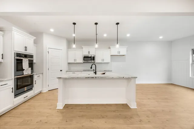 a view of a kitchen with kitchen island a sink stainless steel appliances and cabinets
