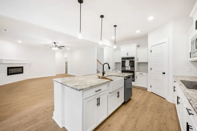 a kitchen with stainless steel appliances granite countertop a sink a stove and a wooden floor