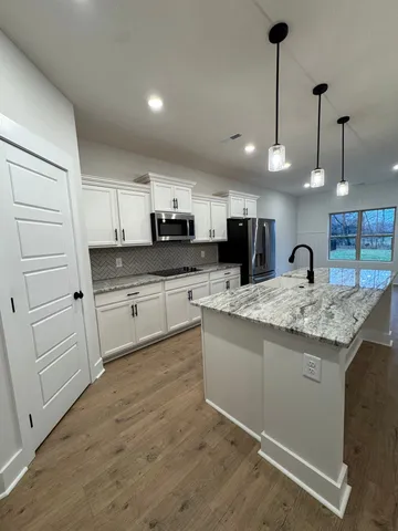 a kitchen with kitchen island granite countertop stainless steel appliances lots of counter space sink and cabinets