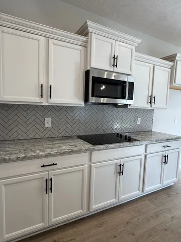 a kitchen with granite countertop white cabinets and a sink