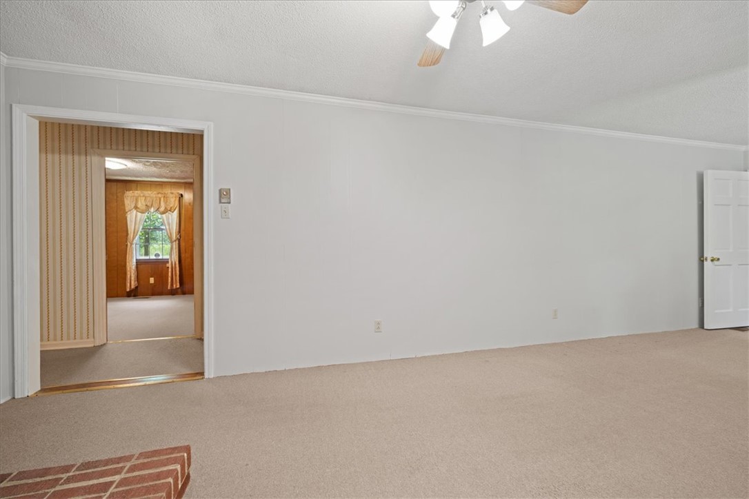 304 Shaw Road Honea Path, SC 29654 - Photo 8 of 39 This inviting living space features soft carpeting and a classic ceiling fan, offering a comfortable atmosphere.