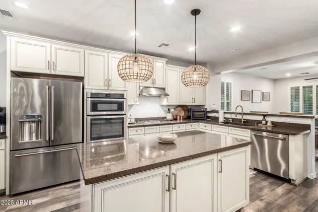 a kitchen with stainless steel appliances granite countertop a sink a stove a refrigerator a center island and cabinets