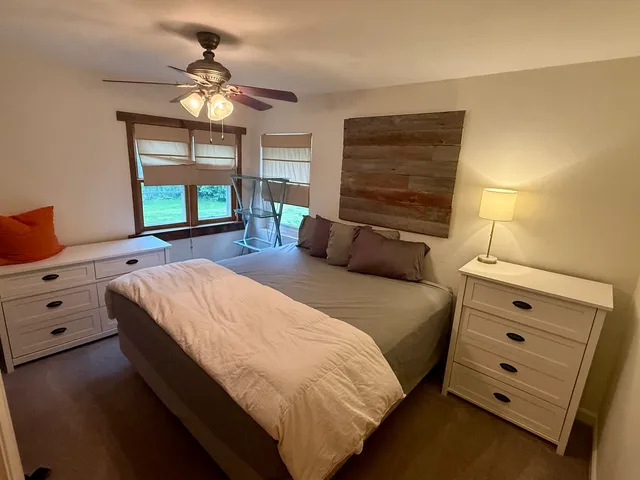 a bedroom with a bed a chandelier and a dresser