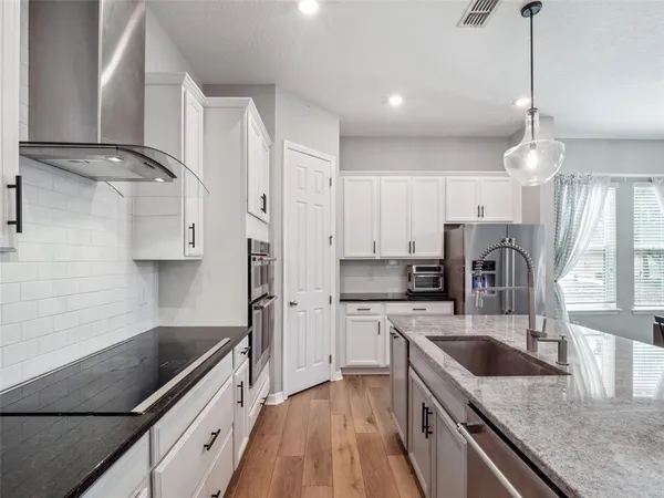 a kitchen with stainless steel appliances granite countertop a sink a stove and a wooden floors