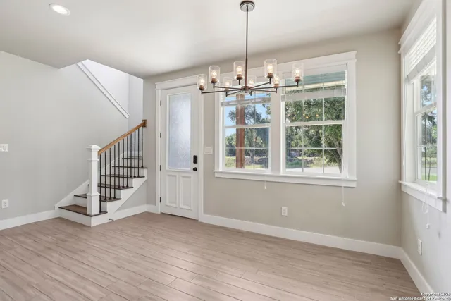 a view of an empty room with wooden floor fridge and a window