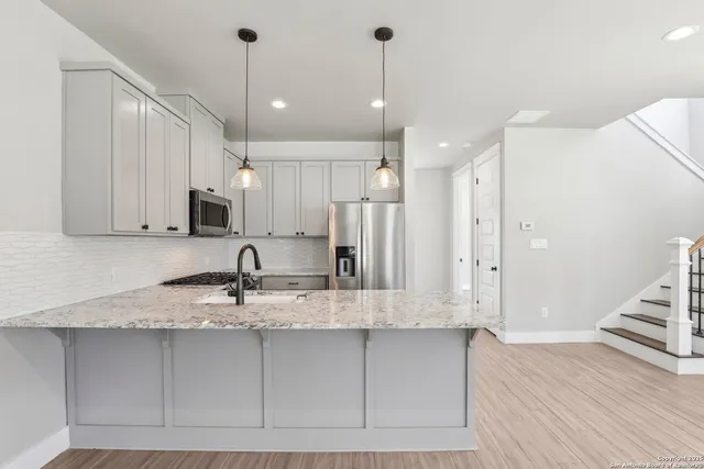 a kitchen with kitchen island granite countertop a sink a counter space appliances and cabinets