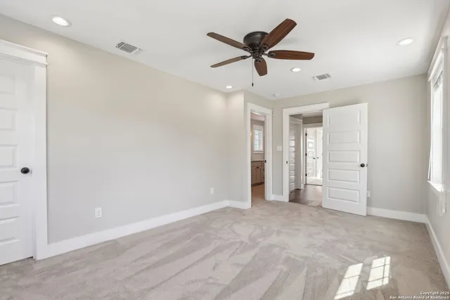 a view of a livingroom with a ceiling fan & windows
