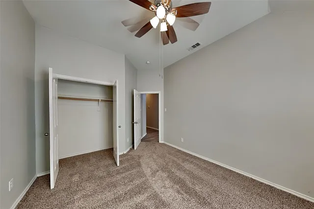 an empty room with closet and a chandelier fan