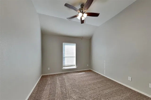 an empty room with a chandelier fan and windows