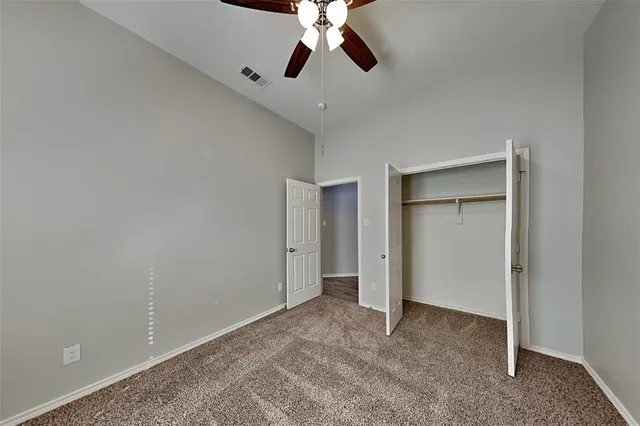 a view of an empty room and chandelier fan