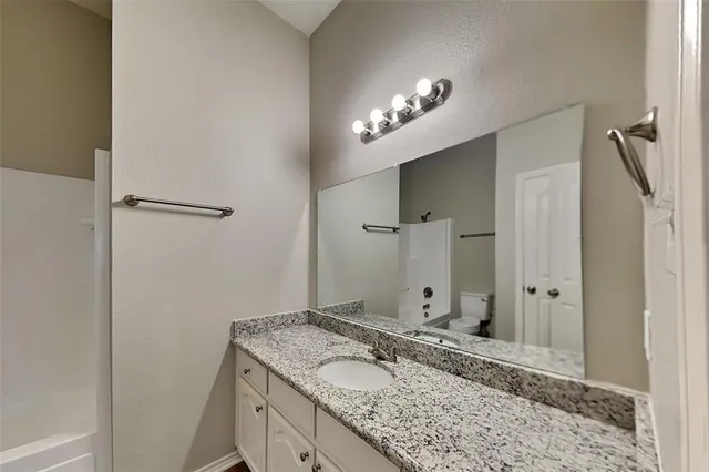 a bathroom with a granite countertop sink a large mirror and a shower