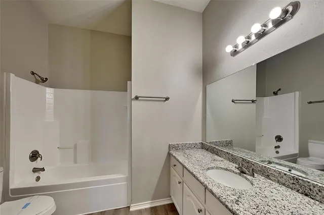 a bathroom with a granite countertop sink a large mirror and a bathtub