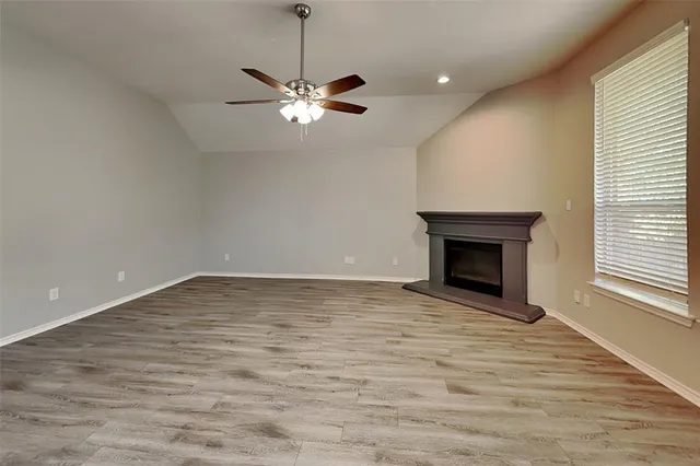 a view of empty room with wooden floor fireplace and window