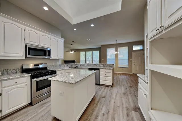 a large kitchen with cabinets wooden floor and stainless steel appliances