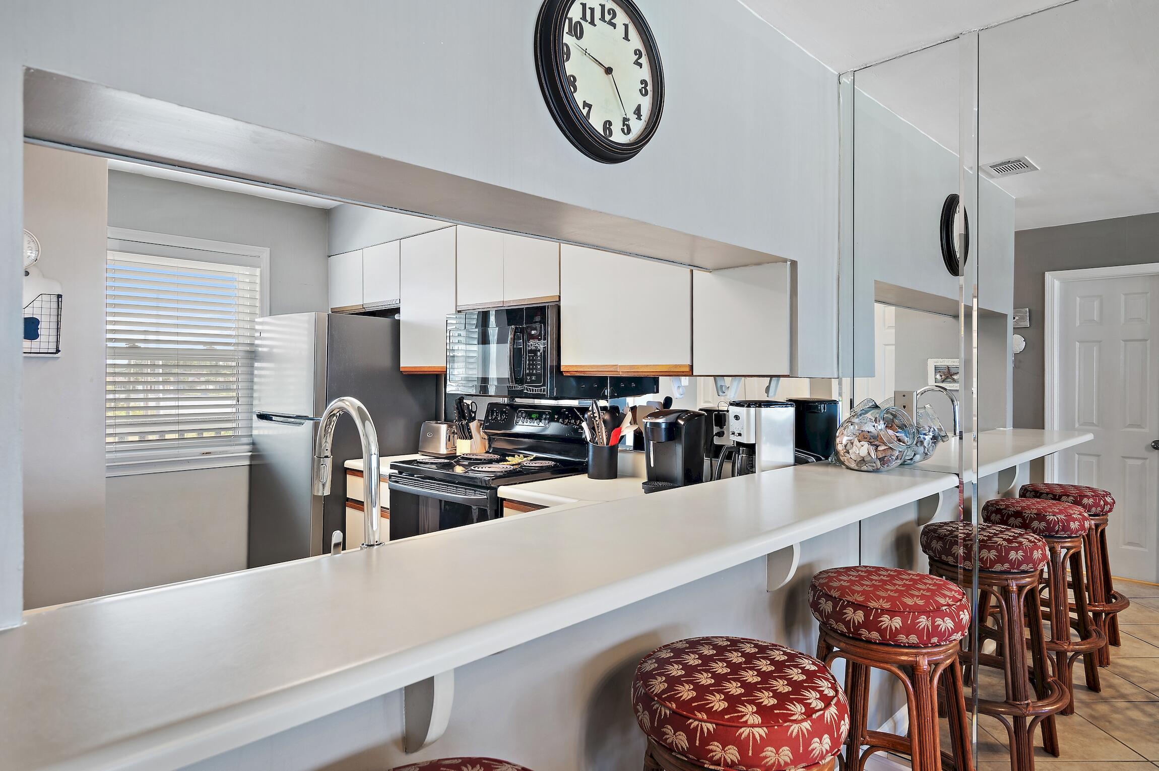23011 Front Beach Road, Unit 24 Panama City Beach, FL 32413 - Photo 10 of 23 a kitchen with stainless steel appliances granite countertop a dining table chairs stove and white cabinets