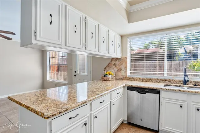 a kitchen with granite countertop white cabinets and a sink