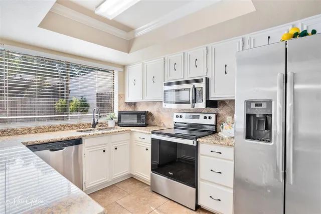 a kitchen with granite countertop a sink stainless steel appliances and cabinets