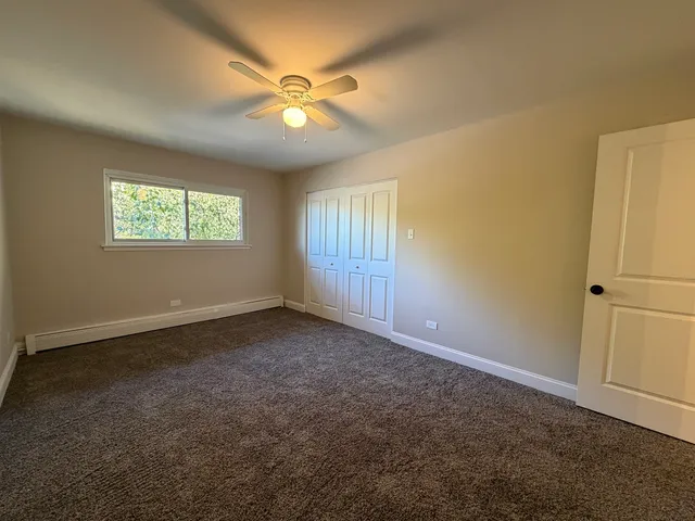 an empty room with windows and fan