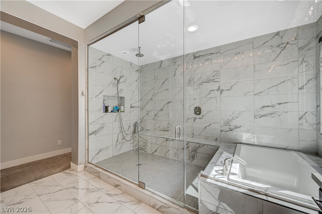 3943 Reyes Avenue Las Vegas, NV 89141 - Photo 36 of 95 A glass-enclosed shower and adjacent soaking tub offer a serene spa-like experience in this elegant bathroom.