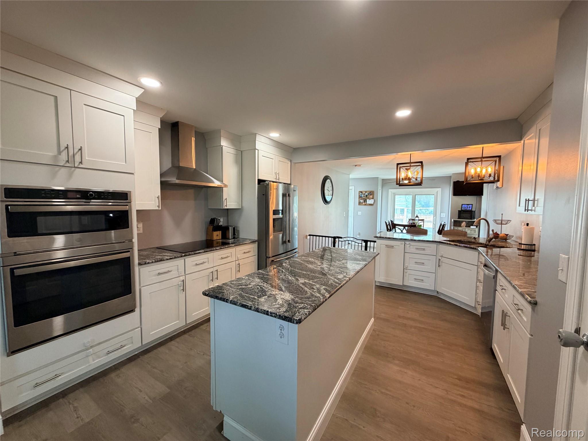 3840 East Dunbar Road Monroe, MI 48161 - Photo 17 of 38 Kitchen featuring white cabinetry, stainless steel appliances including a wall oven and microwave, a center island with a stone countertop, and wood-finish flooring