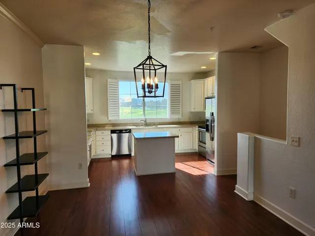 a kitchen with kitchen island stainless steel appliances a sink and wooden floor