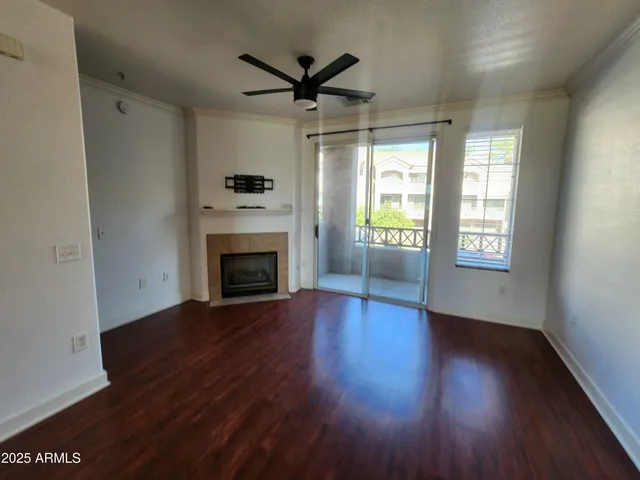 an empty room with wooden floor a ceiling fan and windows