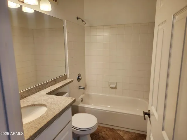 a bathroom with a granite countertop bathtub shower sink vanity and toilet