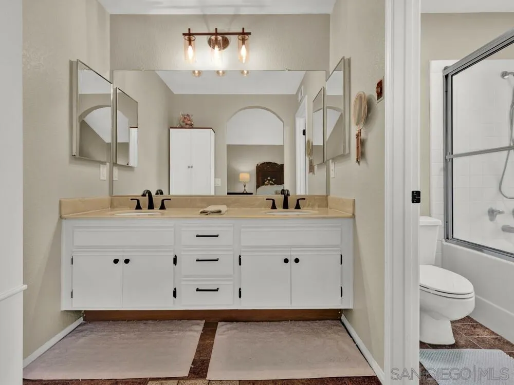 1591 Madrid Drive Vista, CA 92081 - Photo 17 of 40 a bathroom with a sink a toilet and a mirror