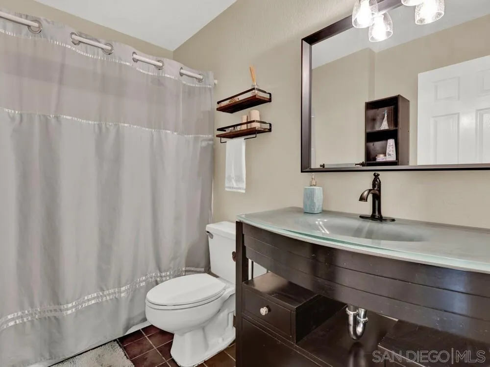 1591 Madrid Drive Vista, CA 92081 - Photo 19 of 40 a bathroom with a granite countertop sink toilet and a mirror